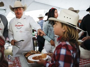 Albertas Premier Jason Kenney, links, serviert Pfannkuchen beim jährlichen Stampede-Frühstück seines letzten Premiers als Premier in Calgary, Alta, Montag, 11. Juli 2022.