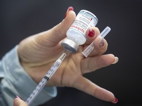 A person draws out Moderna vaccine during a drive through COVID-19 vaccine clinic at St. Lawrence College in Kingston, Ont., on Jan. 2, 2022.
