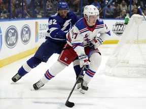 Rangers defenceman Nils Lundkvist (27) carries the puck in front of Lightning left wing Gabriel Fortier (82) during second period NHL action Dec. 31, 2021, in Tampa, Fla.