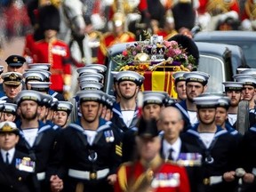 Royal Navy Sailors walk ahead and behind the coffin of Queen Elizabeth II, draped in the Royal Standard, as it travels from Westminster Abbey to Wellington Arch in London on Sept. 19, 2022.