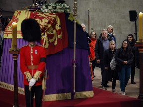 Mitglieder der öffentlichen Akte kommen am flaggenbehangenen Sarg von Königin Elizabeth II. vorbei, der im Staat auf dem Katafalk liegt, als sie mitten in der Nacht am 17. September 2022 in London die Westminster Hall betreten.