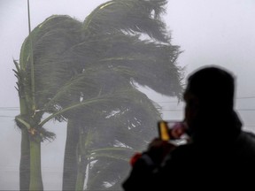 A man livestreams as gusts from Hurricane Ian hits in Punta Gorda, Fla., on Sept. 28, 2022.