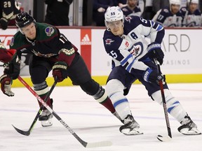 Mark Scheifele (55) of the Winnipeg Jets skates with the puck against Nick Bjugstad (17) of the Arizona Coyotes during the first period of the NHL game at Mullett Arena on Oct. 28, 2022 in Tempe, Arizona.