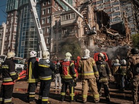 Ukrainische Feuerwehrleute arbeiten an einem zerstörten Gebäude nach einem Drohnenangriff in Kiew am 17. Oktober 2022 inmitten der russischen Invasion in der Ukraine (Foto von YASUYOSHI CHIBA/AFP über Getty Images)