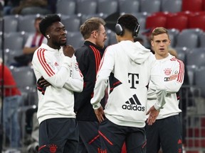 Alphonso Davies, left, chats with his Bayern Munich teammates before a match against SC Freiburg at Allianz Arena in Munich, Germany, Sunday, Oct. 16, 2022.