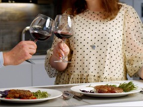 Happy couple enjoying romantic dinner at home with roasted steak and red wine