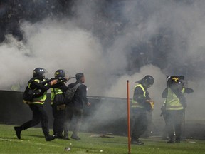 A riot police officer fires tear gas during riot after the league BRI Liga 1 football match between Arema vs Persebaya at Kanjuruhan Stadium, Malang, East Java province, Indonesia, October 2, 2022.