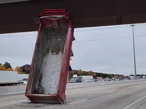 The empty box of a dump truck is seen wedged under a pedestrian overpass on Hwy. 401 approaching Mavis Rd. in Mississauga on Wednesday morning.