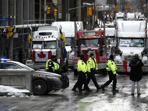 Polizisten patrouillieren zu Fuß entlang der Albert Street, um gegen die COVID-19-Beschränkungen zu protestieren, die von einem Verkehrsinfarkt gekennzeichnet sind und das Hupen von Lastwagen am Donnerstag, den 10. Februar 2022, in Ottawa seinen 14. Tag erreicht.