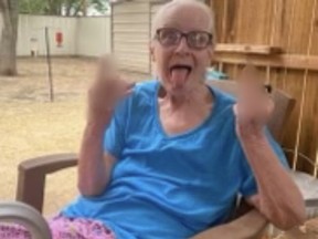 Older woman sticking her tongue out with her two blurred middle fingers up.