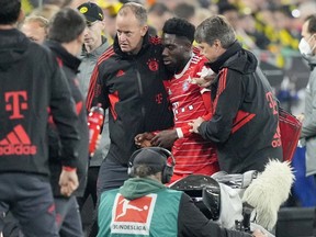 Bayern's Alphonso Davies, centre, leaves the field after getting injured during the German Bundesliga soccer match between Borussia Dortmund and Bayern Munich in Dortmund, Germany, Saturday, Oct. 8, 2022. Davies, who had to be helped off the field after taking a boot to the head, was back training Friday with Bayern Munich.