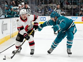 Alex DeBrincat #12 of the Ottawa Senators skates with the puck defended by Nick Bonino #13 of the San Jose Sharks during the third period of an NHL hockey game at SAP Center on November 21, 2022 in San Jose, California. The Sharks won the game 5-1.