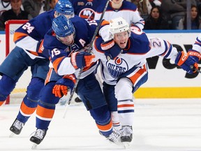 ELMONT, NEW YORK - NOVEMBER 23: Cal Clutterbuck #15 of the New York Islanders attempts to get past Tyson Barrie #22 of the Edmonton Oilers during the second period at the UBS Arena on November 23, 2022 in Elmont, New York.