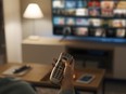 Young woman relaxing on the couch at home and watching videos on streaming service on her TV.