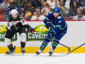 Vancouver Canucks' Bo Horvat (right) passes around Arizona Coyotes defenceman Conor Timmins during a game in Vancouver on Oct. 7, 2022. The Maple Leafs acquired Timmins on Wednesday.