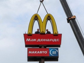 Workers use a crane to dismantle the McDonald's Golden Arches while removing the logo signage from a drive-through restaurant in the town of Kingisepp in the Leningrad region, Russia, June 8, 2022.