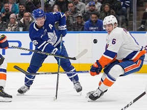 New York Islanders' Ryan Pulock and Maple Leafs' Mitchell Marner (left) battle for the puck during the first period at Scotiabank Arena on Monday, Nov. 21, 2022.