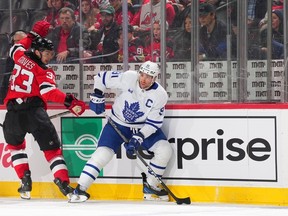 John Tavares of the Maple Leafs controls the puck against Ryan Graves of the New Jersey Devils during the second period at the Prudential Center on Wednesday, Nov. 23, 2022 in Newark.