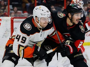 Ottawa Senators defenseman Travis Hamonic (right) checks Anaheim Ducks left winger Max Jones during an NHL game at the Canadian Tire Centre on Dec. 12, 2022.
