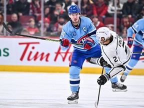 Canadiens' Nick Suzuki (14) delivers a check on Alexander Edler (2) of the Los Angeles Kings during the second period at the Bell Centre on Saturday, Dec. 10, 2022, in Montreal.
