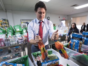 Prime Minister Justin Trudeau loads food baskets at a food bank in Montreal, on Dec. 20, 2022.