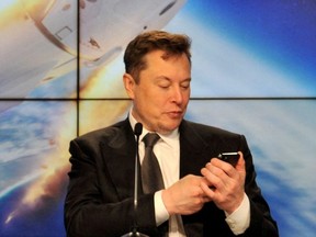 Elon Musk looks at his mobile phone at the Kennedy Space Center in Cape Canaveral, Fla., Jan. 19, 2020.