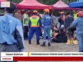 Rescued people sit on mats after a landslide in Batang Kali, Malaysia, Friday, Dec. 16, 2022 in this still image taken from video.