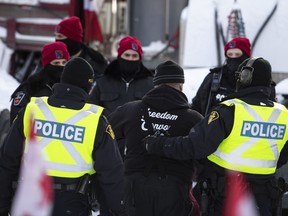 A trucker is led away after leaving his truck as police aim to end an ongoing protest against COVID-19 measures that has grown into a broader anti-government protest, on its 22nd day, in Ottawa, on Friday, Feb. 18, 2022.