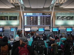 Passengers wait in a check-in line at Vancouver International Airport after a snowstorm crippled operations leading to cancellations and major delays, in Richmond, B.C., on Tuesday, Dec. 20, 2022.