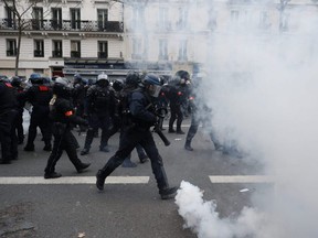 Riot police officers run through tear gas during a demonstration against pension changes, in Paris, Thursday, Jan. 19, 2023.