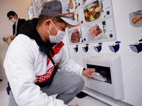 A customer buys whale meat on the opening day of a shop by a Japanese whale-hunting company with vending machines in Yokohama, Japan, Tuesday, Jan. 24, 2023.
