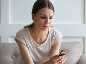 Unhappy woman looking at cellphone screen.