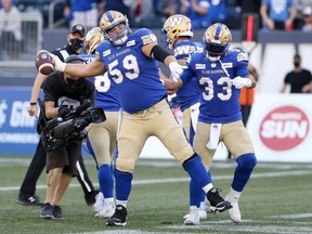 Winnipeg Blue Bombers RB Andrew Harris (right) shadows OL Michael Couture after handing him the ball to help celebrate his rushing touchdown against the Calgary Stampeders during the 2021 season. Couture officially joined the B.C. Lions as a free agent on Tuesday.