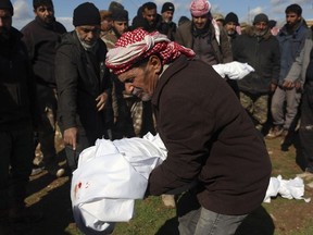 Mourners bury family members who died in a devastating earthquake that rocked Syria and Turkey at a cemetery in the town of Jinderis, Aleppo province, Syria, Tuesday, Feb. 7, 2023.