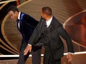Will Smith (right) hits Chris Rock as Rock spoke on stage during the 94th Academy Awards in Hollywood, Calif., March 27, 2022.