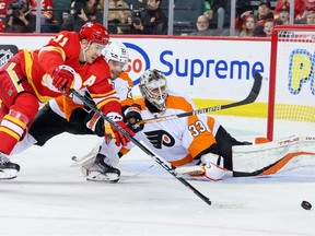 Calgary Flames forward Mikael Backlund and Philadelphia Flyers forward Scott Laughton battle for the puck in front of Flyers goaltender Samuel Ersson at Scotiabank Saddledome in Calgary on Monday, Feb. 20, 2023.