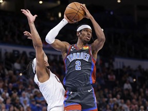 Oklahoma City Thunder guard Shai Gilgeous-Alexander, right, looks to pass the ball away from Cleveland Cavaliers forward Lamar Stevens during the second half of an NBA basketball game Friday, Jan. 27, 2023, in Oklahoma City.