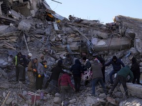 People carry a dead body from a collapsed building in Kahramanmaras, southern Turkey, Wednesday, Feb. 8, 2023.