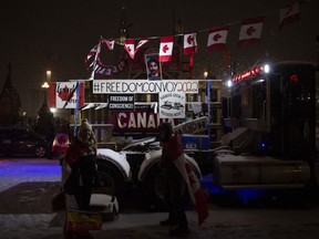 Snow falls as protesters stand by a semi-trailer truck on Wellington Street, on the 21st day of a protest against COVID-19 measures that had grown into a broader anti-government protest, in Ottawa, on Thursday, Feb. 17, 2022.