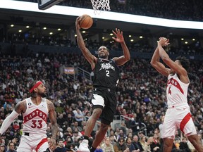 LA Clippers forward Kawhi Leonard (2) goes up to make a basket against Toronto Raptors guard Gary Trent Jr. (33) and forward Scottie Barnes (4) at Scotiabank Arena.