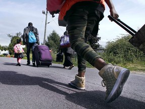 Migrants make the trek across the border in Quebec walking down Roxham Road in Champlain, N.Y., on Aug. 7, 2017.