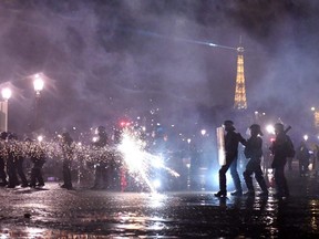 A protester shoots fireworks at police officers, with the Eiffel tower seen in the background, during a demonstration on Place de la Concorde in Paris, Friday, March 17, 2023.