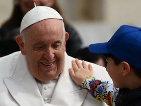 A boy pats Pope Francis on the shoulder while leaving in the popemobile on Wednesday, March 29, 2023 at the end of the weekly general audience at St. Peter's square in The Vatican.
