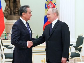 Russia's President Vladimir Putin shakes hands with China's Director of the Office of the Central Foreign Affairs Commission Wang Yi during a meeting in Moscow, Russia, Feb. 22, 2023.