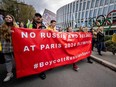 Ukrainians walk past the headquarters of International Olympic Committee (IOC) during a protest against the proposed IOC roadmap to organise the return to competition of Russian athletes under a neutral flag, provided that they have "not actively supported the war in Ukraine" in Lausanne on March 25, 2023.