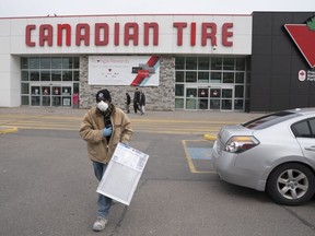 A man wearing a mask walks out of a Canadian Tire store in Toronto on Wednesday March 18, 2020.
