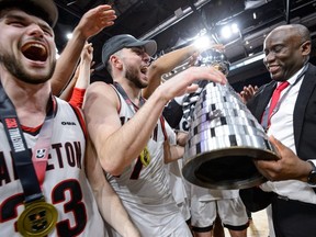 Halifax, Nova Scotia - Mar 12, 2023: USports Men's Final 8 National Basketball Gold Medal Championship game between Carleton Ravens and St FX XMen at the Scotiabank Center in Halifax, Nova Scotia. From left, Connor Vreeken, Gebrael Samaha and coach Taffe Charles celebrate after the double-overtime win.
