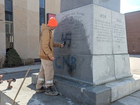 Adin Klaasen, with Memorial Restorations of Sarnia, works on trying to remove a swastika that was spray-painted on the cenotaph in downtown Chatham. (Handout)