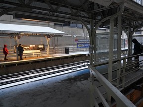 Pedestrians waiting for a Chicago Transit Authority train in Chicago's famed Loop stand in a warming station, left, as another waits alone Thursday, Dec. 22, 2022.