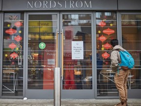 A man stands in front of the Nordstrom store, closed for in-store shopping in downtown Toronto on Nov. 23, 2020.